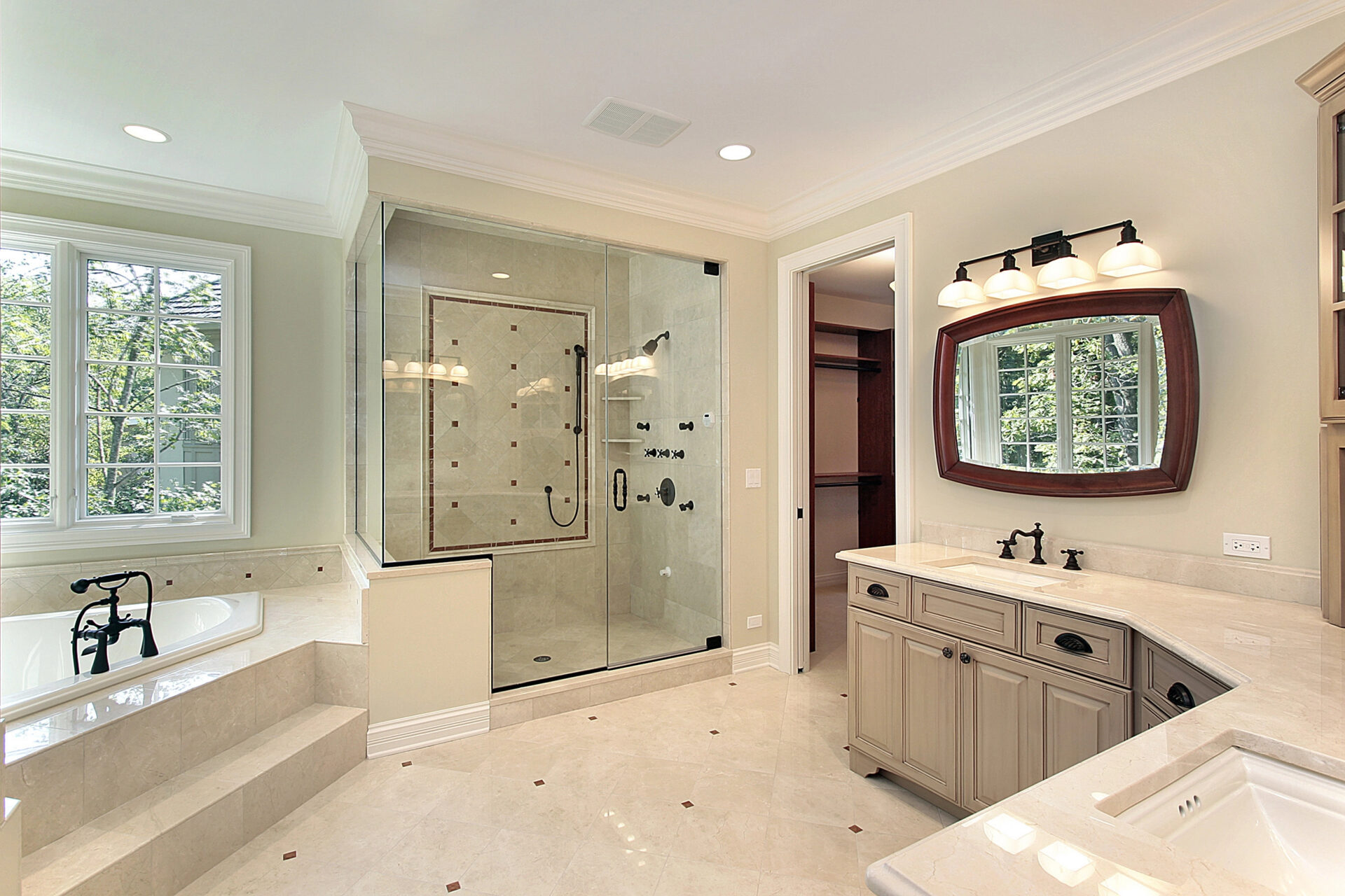 Spacious bathroom with a glass shower, built-in bathtub, double-sink vanity with mirror, and natural light from large windows.